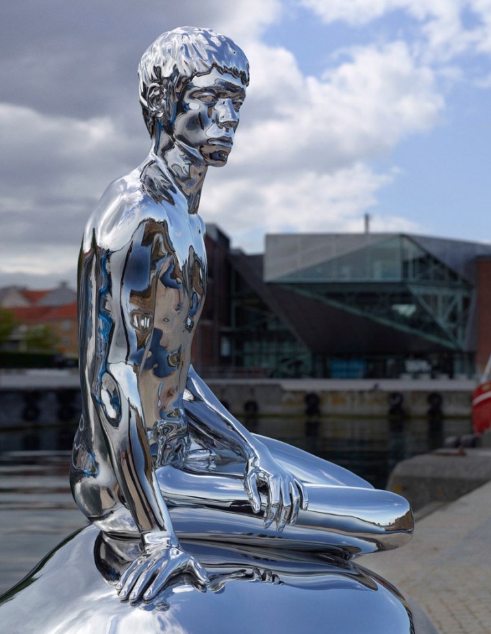 stainless steel sculpture of a man sitting on the rock 2