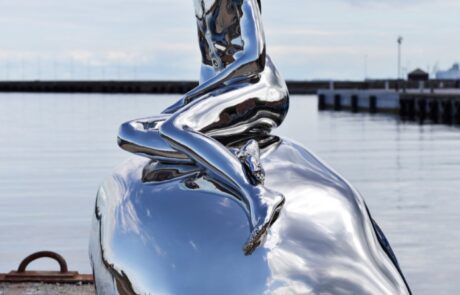 stainless steel sculpture of a man sitting on the rock
